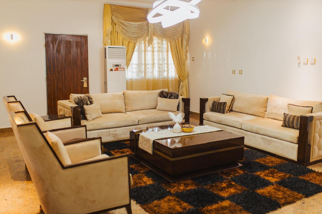 Main parlor with cream suede sofas, gold curtains and a wood coffee table