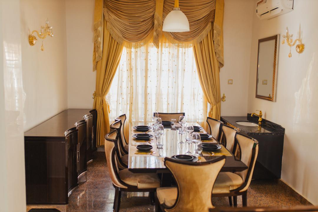 Formal dining room seating eight beneath gold drapes
